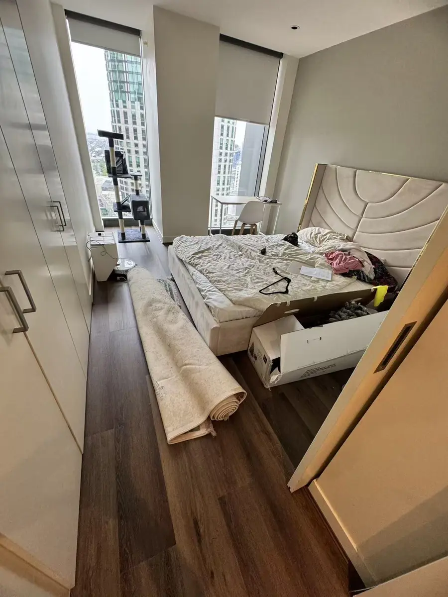 Dark plank flooring in a bedroom with a rolled rug and built-in wardrobe